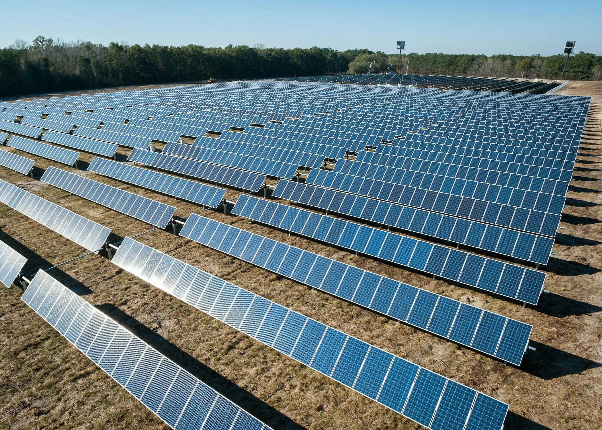 Rows of ground-mounted solar panels on dry, dusty ground